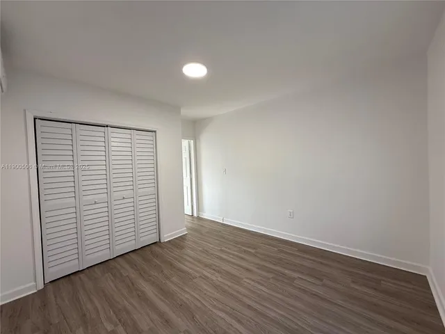 a view of an empty room with wooden floor and closet