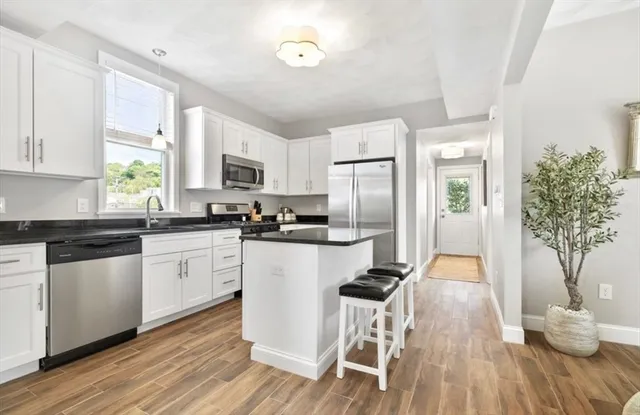a kitchen with granite countertop white cabinets and stainless steel appliances