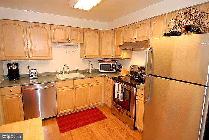173 West Annandale Road Falls Church, VA 22046 - Photo 6 of 25 a kitchen with stainless steel appliances granite countertop a refrigerator a stove a sink and white cabinets with wooden floor