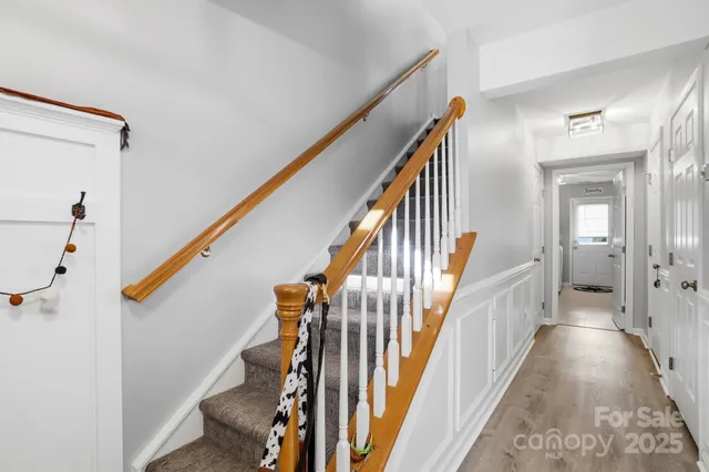 a view of staircase with lots of frames on wall and wooden floor