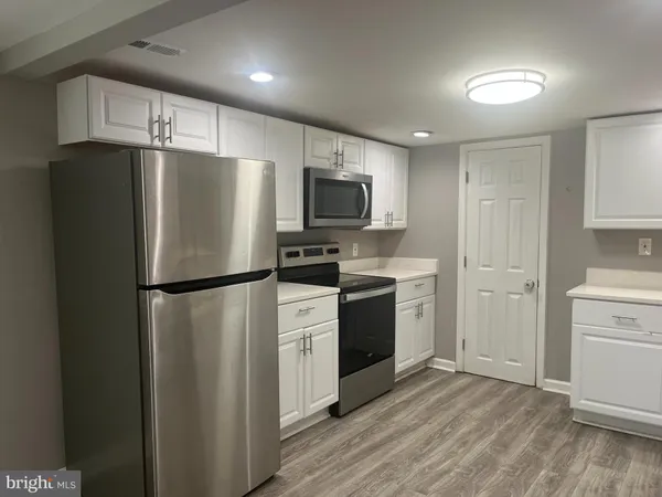 a kitchen with a refrigerator a stove top oven and cabinets