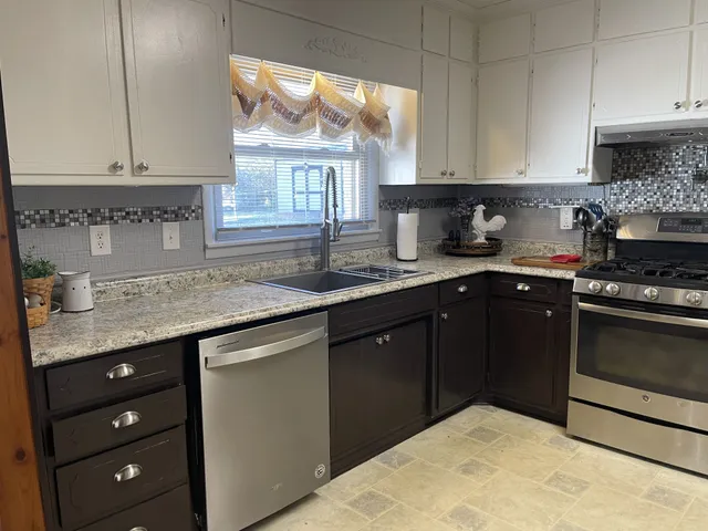 a kitchen with granite countertop a sink stainless steel appliances and cabinets