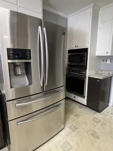 a metallic refrigerator freezer sitting inside of a kitchen