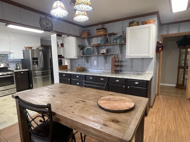 a kitchen with stainless steel appliances a table and chairs in it