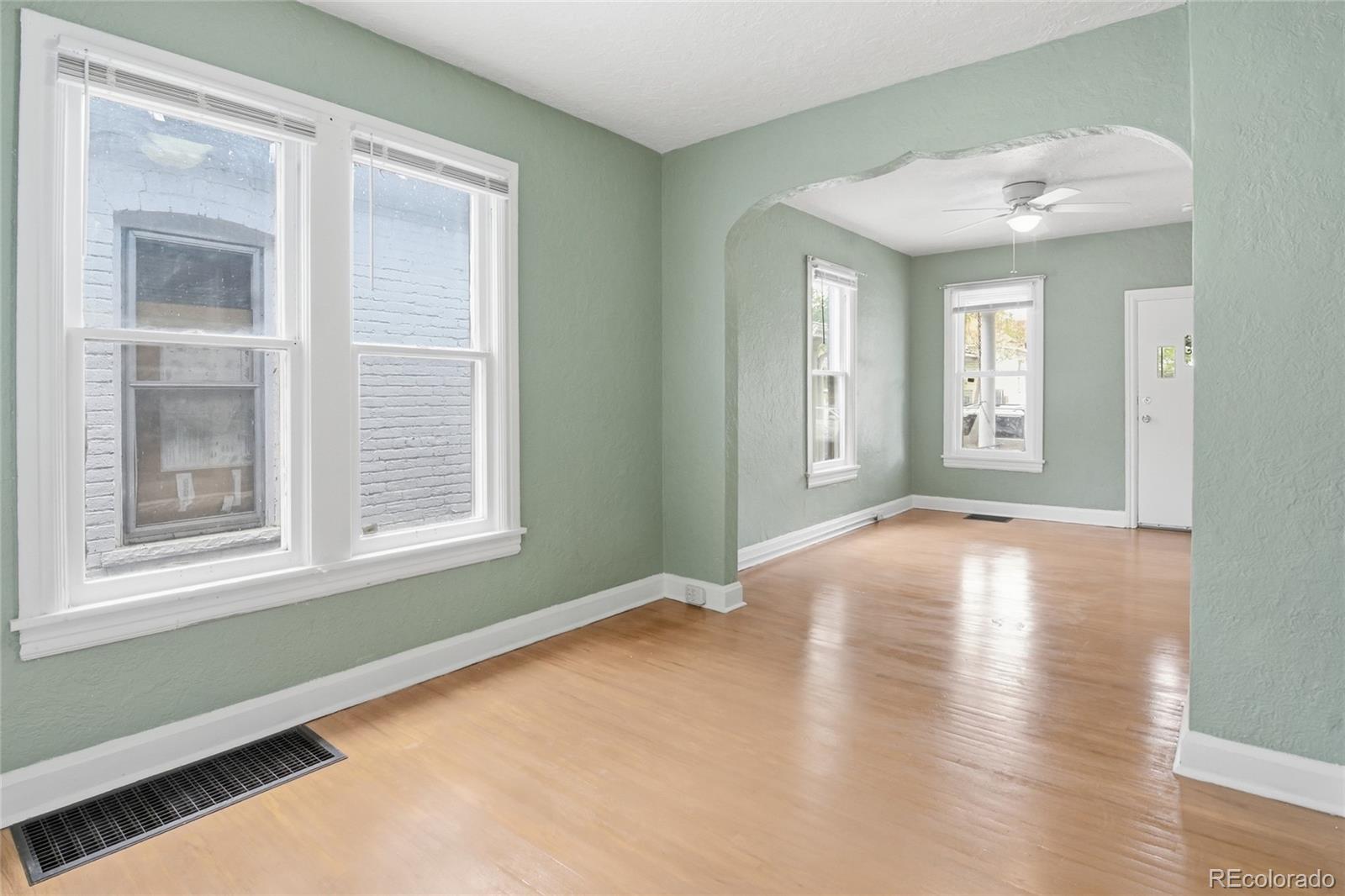 4424 Sherman Street Denver, CO 80216 - Photo 4 of 16 an empty room with wooden floor and windows