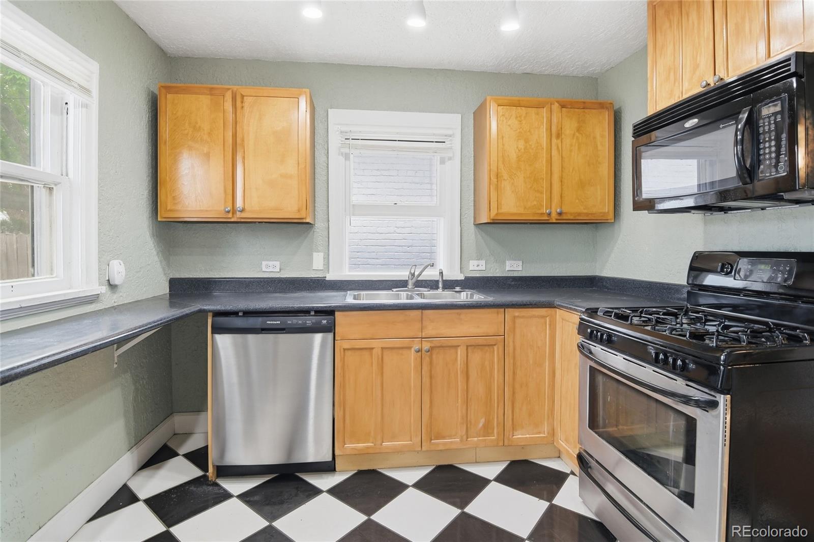 4424 Sherman Street Denver, CO 80216 - Photo 10 of 16 a kitchen with stainless steel appliances granite countertop a stove a sink and a microwave