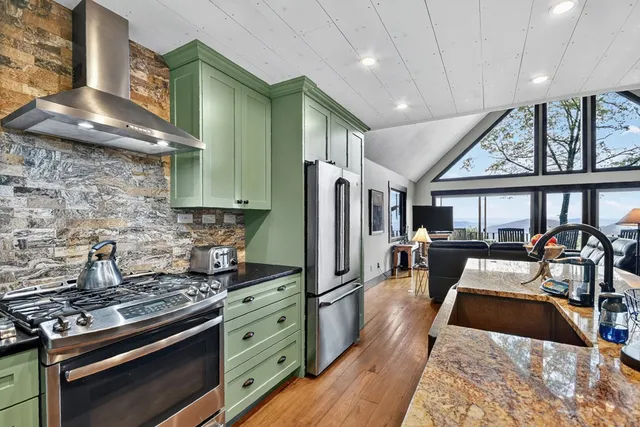 a living room with furniture a rug kitchen view and a window