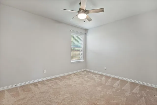 an empty room with a window and ceiling fan
