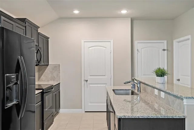 a kitchen with granite countertop a refrigerator and a sink