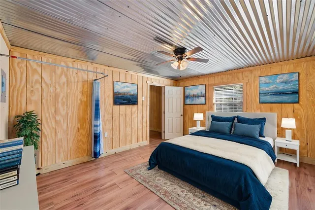 a bedroom with a large bed a chandelier and dresser next to a window