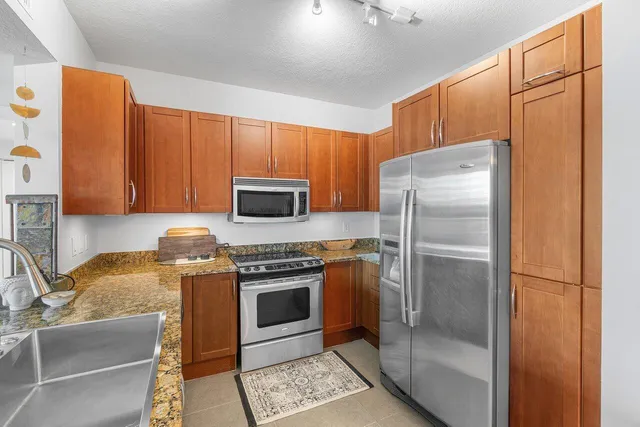 a kitchen with stainless steel appliances granite countertop a refrigerator a stove a sink and dishwasher