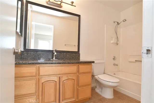 a bathroom with a granite countertop toilet sink and mirror