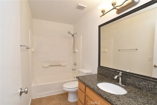 a bathroom with a granite countertop sink toilet a mirror and shower