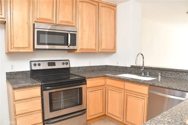a kitchen with granite countertop a sink stove and microwave