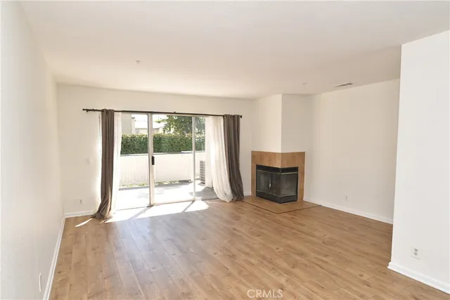 a view of empty room with wooden floor and fireplace