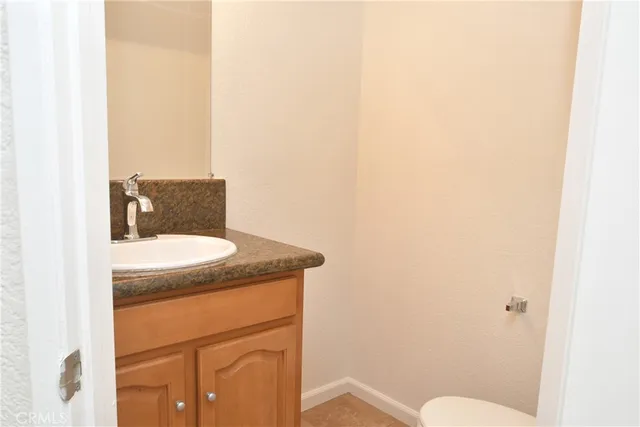 a bathroom with a granite countertop sink and a toilet
