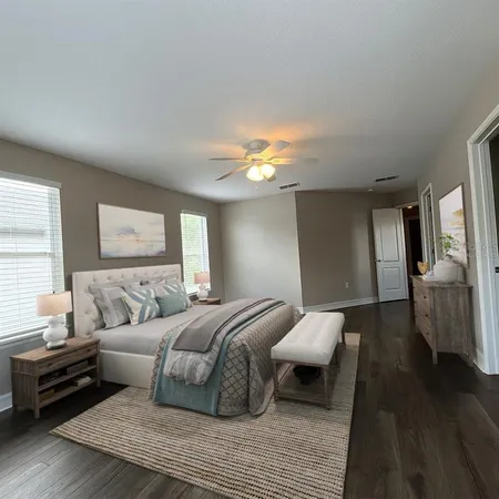 a spacious bedroom with a bed and wooden floor