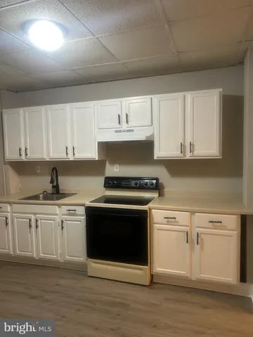 a kitchen with stainless steel appliances granite countertop a stove a sink and white cabinets