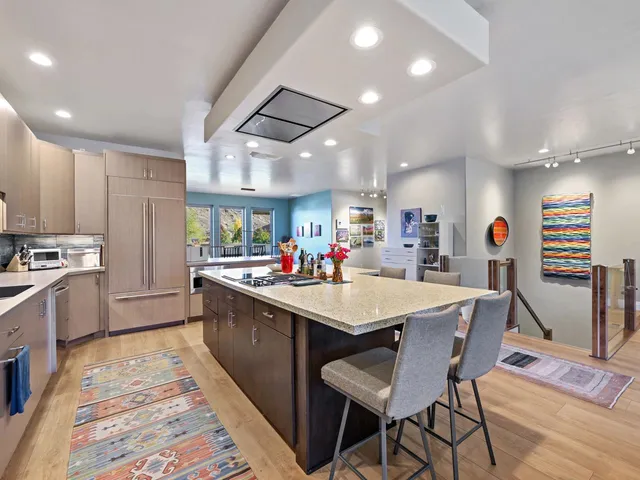 a large kitchen with stainless steel appliances a table chairs refrigerator and cabinets