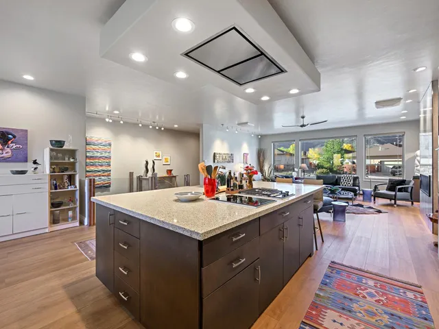 a large kitchen with stainless steel appliances a stove a sink dishwasher and a dining table with the living room view