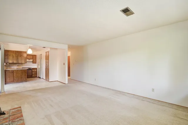 an empty room with kitchen view and a fireplace