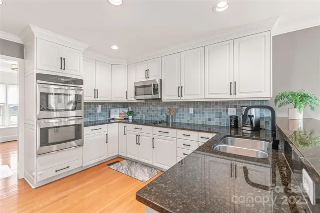 a kitchen with granite countertop white cabinets and white appliances