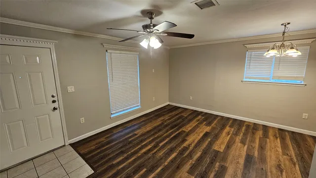a view of an empty room with wooden floor and a ceiling fan