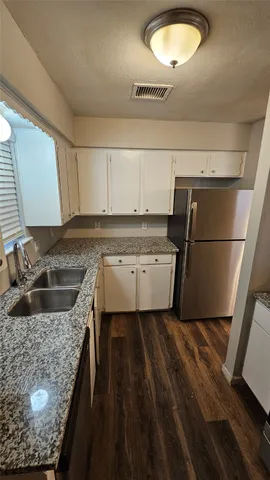 a kitchen with granite countertop a sink a stove and refrigerator