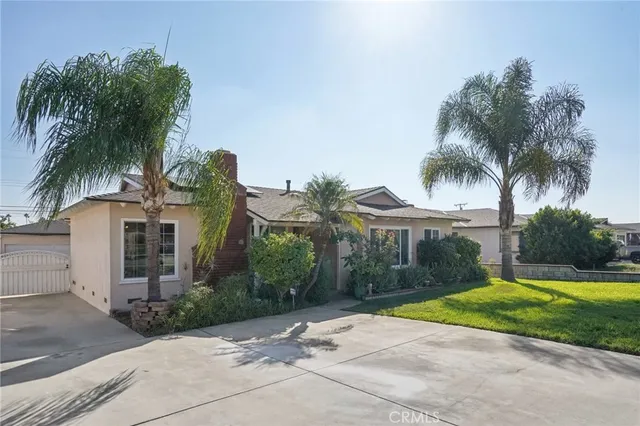 a view of a house with palm trees and a yard with palm trees