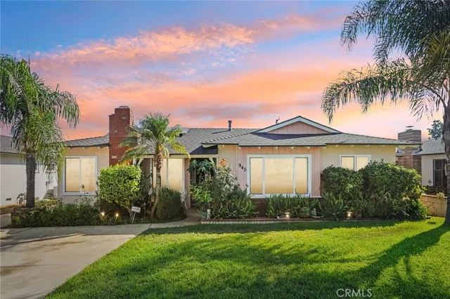 a front view of a house with a garden and palm trees