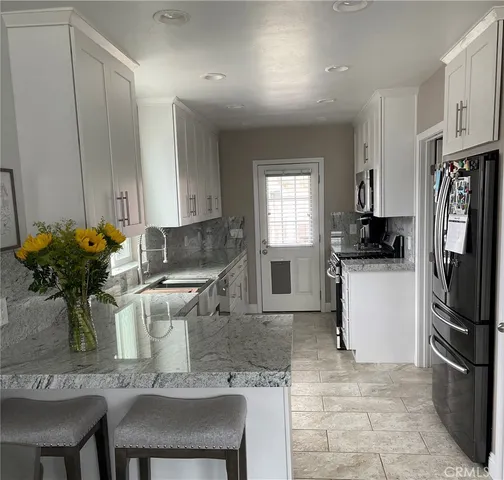 a kitchen with stainless steel appliances granite countertop a refrigerator and a stove top oven