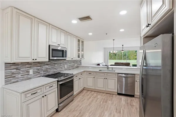 a kitchen with stainless steel appliances granite countertop a stove top oven a sink and white cabinets