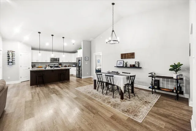 a kitchen with stainless steel appliances kitchen island granite countertop a stove a sink a microwave a dining table and chairs with wooden floor