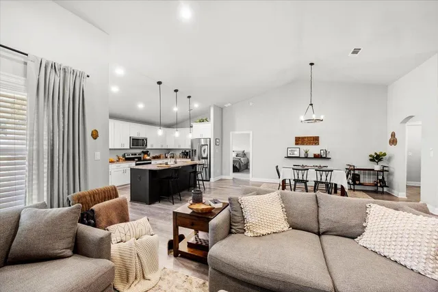 a living room with furniture kitchen view and a chandelier