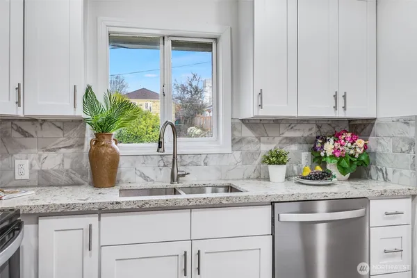 a kitchen with granite countertop a sink a stove and potted plant