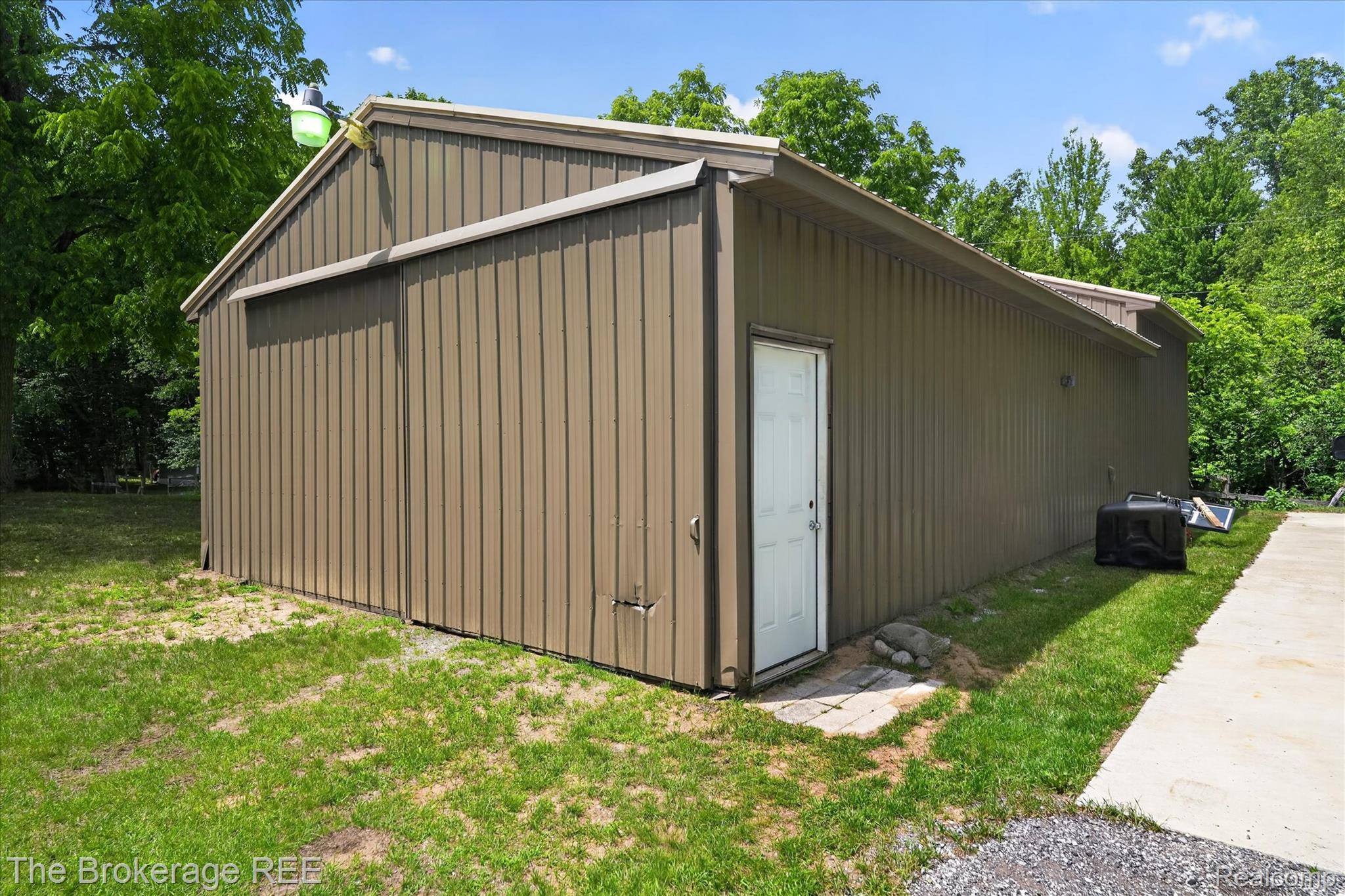 13269 North Genesee Road Clio, MI 48420 - Photo 6 of 67 Metal utility building featuring a corrugated exterior, a white entry door, and an attached floodlight