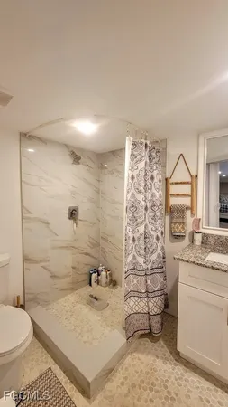 a bathroom with a granite countertop sink a toilet and shower