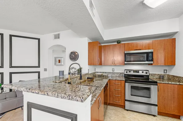 a kitchen with kitchen island granite countertop a sink cabinets and stainless steel appliances