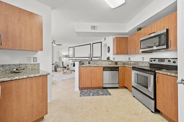 a kitchen with stainless steel appliances granite countertop a stove top oven a sink a counter top space and cabinets