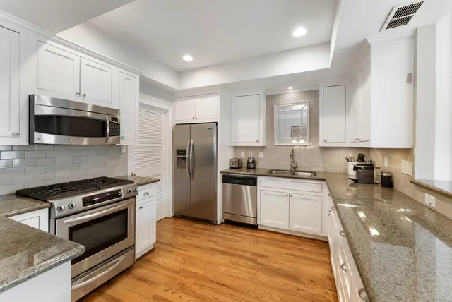 a kitchen with stainless steel appliances a stove a sink a microwave a refrigerator and cabinets