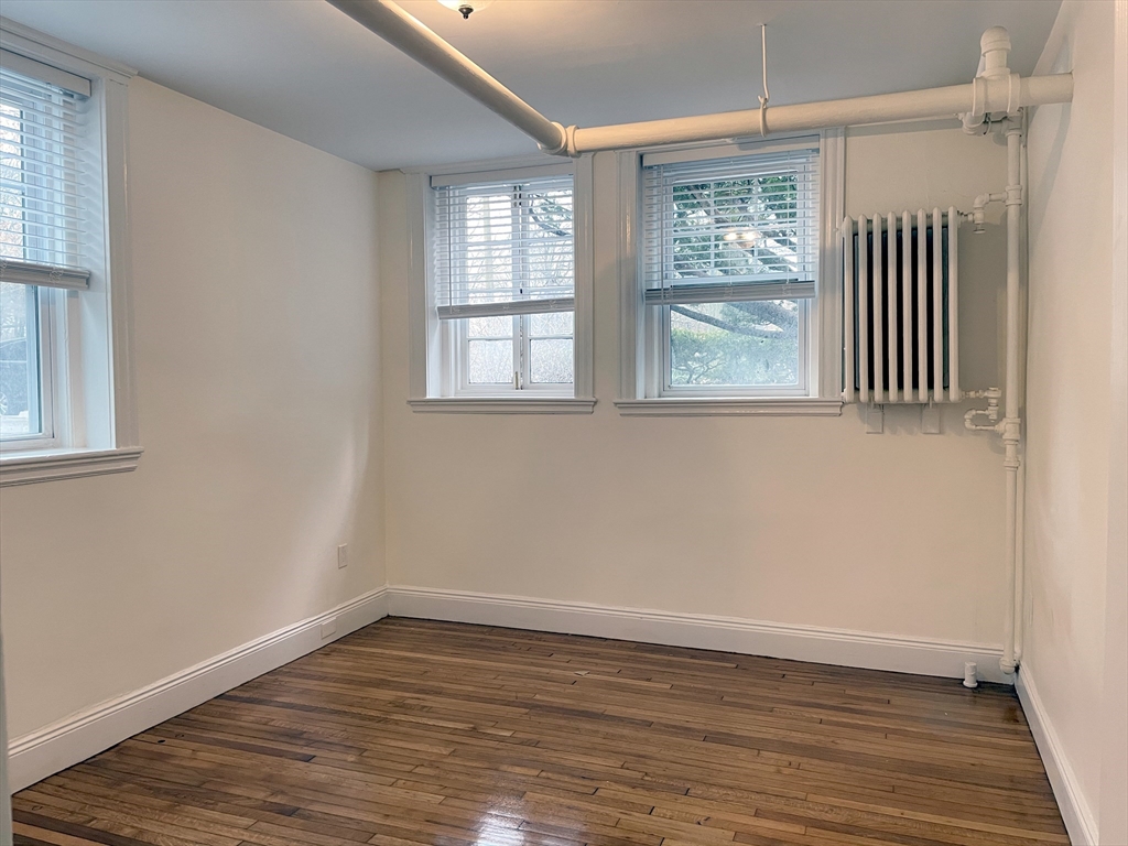 15 Thatcher Street, Unit B Brookline, MA 02446 - Photo 5 of 8 an empty room with wooden floor and windows