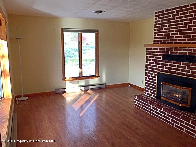 1668 Pennay Hill Road Kingsley, PA 18826 - Photo 8 of 23 an empty room with wooden floor a fireplace and windows