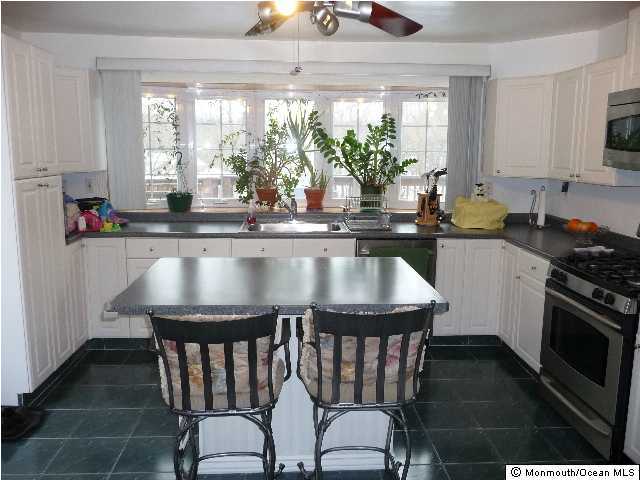 14 Nolan Road Morganville, NJ 07751 - Photo 3 of 3 a kitchen with granite countertop a table chairs stove and cabinets