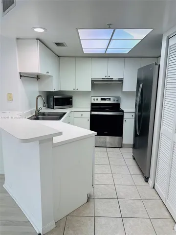 a kitchen with stainless steel appliances a sink a stove a refrigerator and cabinets