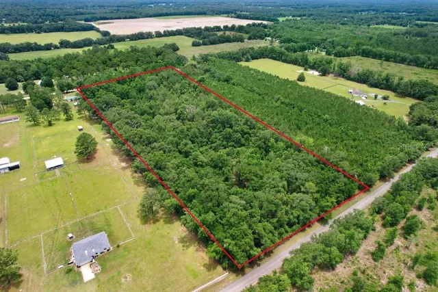 an aerial view of residential houses with outdoor space and trees all around