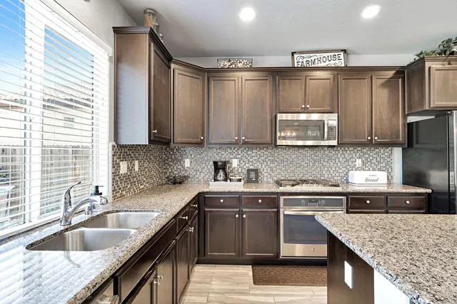 a kitchen with stainless steel appliances granite countertop a sink stove and microwave