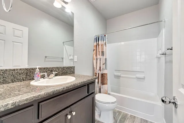 a bathroom with a granite countertop sink toilet and shower