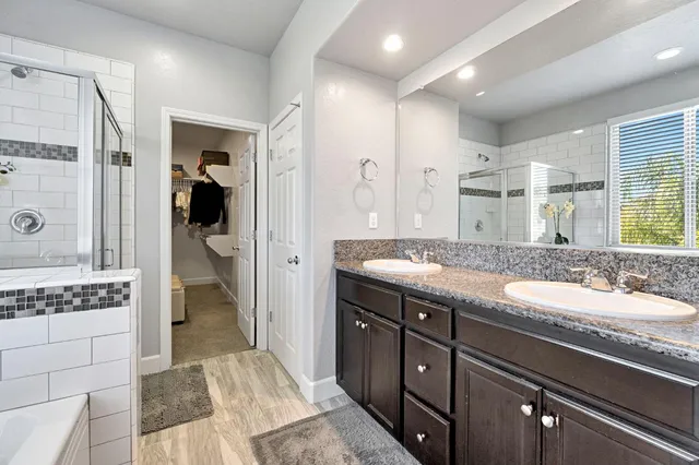 a spacious bathroom with a granite countertop sink a mirror and shower