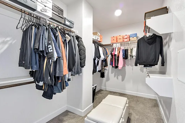 a walk in closet with clothes and shoes