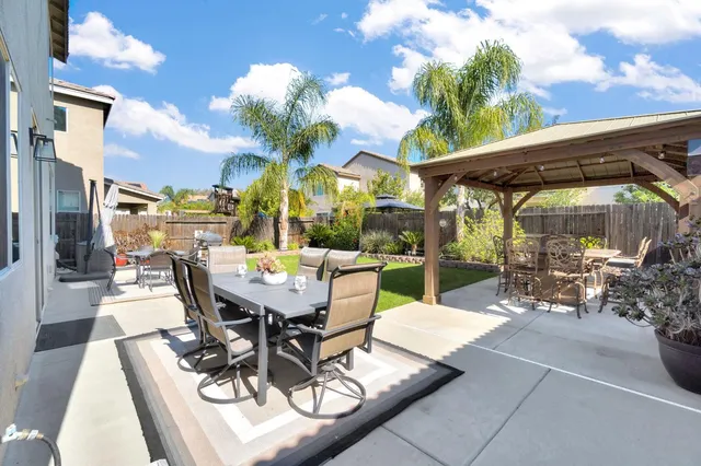 a view of a patio with a dining table and chairs with a small yard